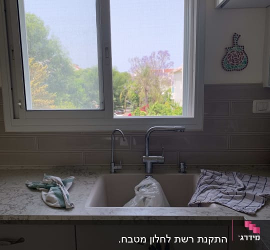 חלון אלומיניום מעל כיור מטבח עם ברזים
